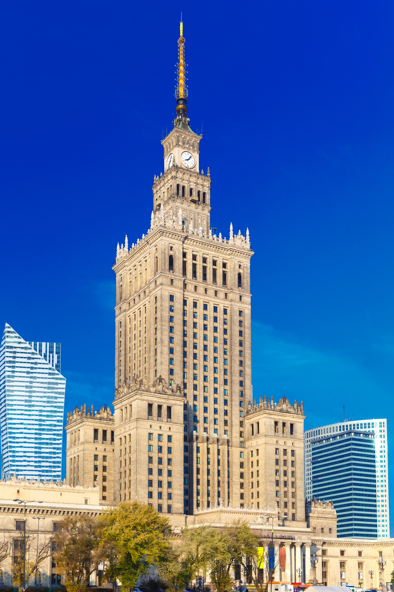 Palace of Culture and Science, a tall historic building with a clock tower in Warsaw, Poland, against a clear blue sky.
